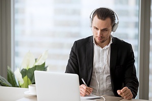 IT professional using remote monitoring and management software on his laptop with headphones for a client in new york city