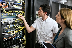 Employees organizing structured network cables in a NYC business server room