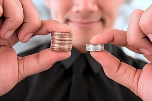 a man holding two stacks of coins to demonstrate higher profits