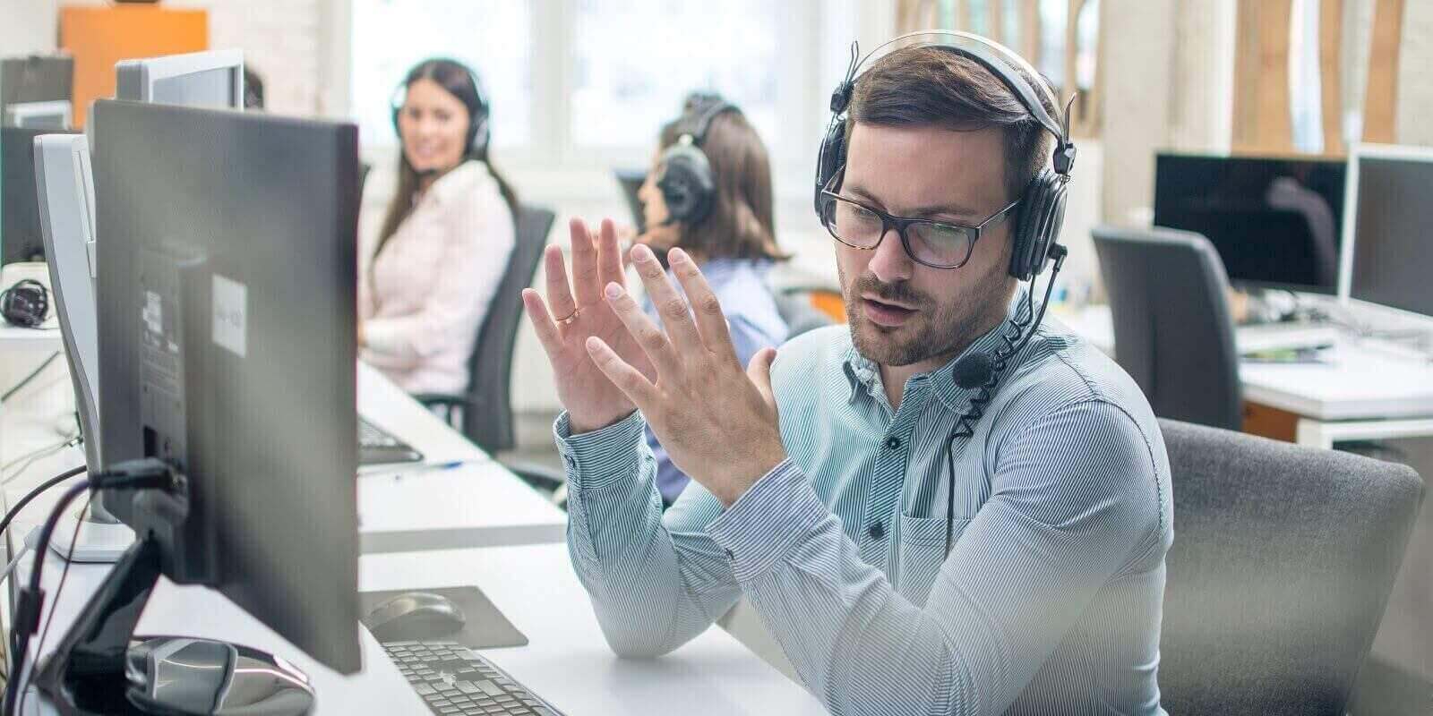 male technical support agent trying to explain something to a client while using hands
